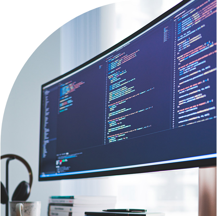 Uno schermo ultrawide con del codice sorgente, cuffie e una tazza su una scrivania di casa